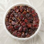 نمای از بالا از چیدمان فشرده دانه‌های درشت و شیره‌دار خرمای کبکاب در ظرف دایره‌ای