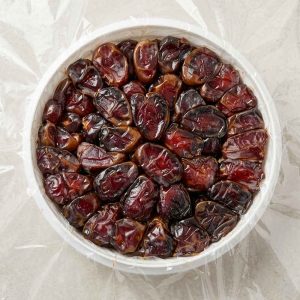 نمای از بالا از چیدمان فشرده دانه‌های درشت و شیره‌دار خرمای کبکاب در ظرف دایره‌ای